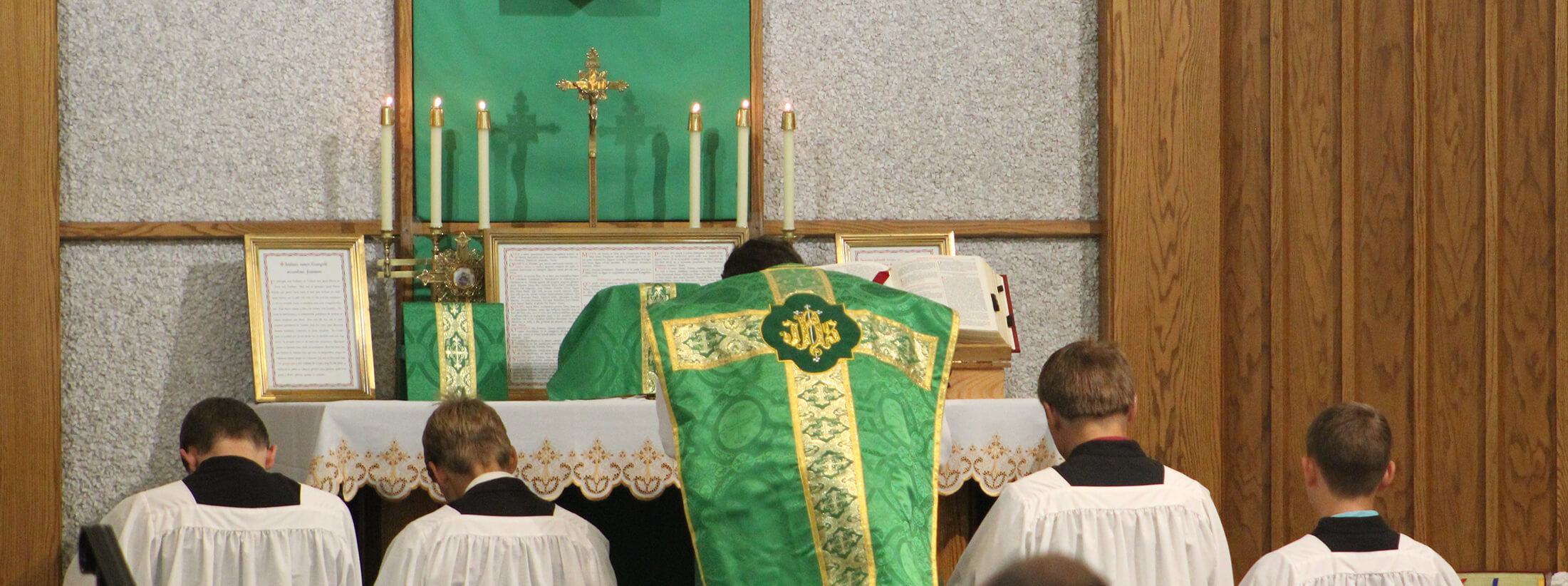 Father praying with altar boys beside