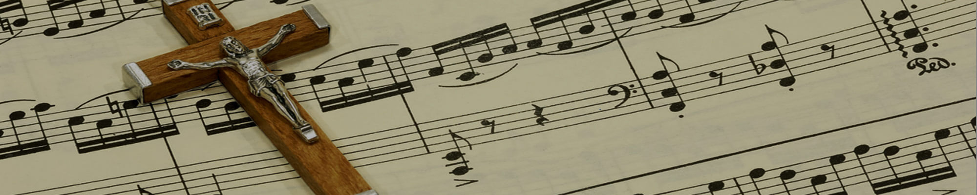 Sheet music with a Catholic Cross of Jesus laid on top of it
